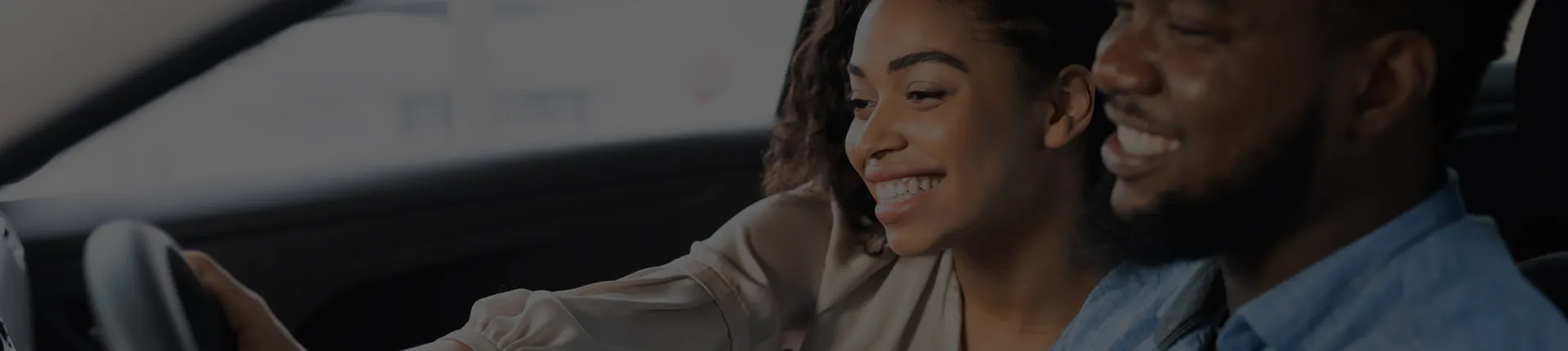 A woman and a man driving a car and smiling